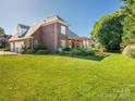 Expansive backyard with lush green lawn and mature trees, complemented by a black fence and pergola covered patio at 725 Old State Sw St, Concord, NC 28027