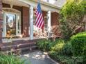 Inviting front porch with rocking chairs, brick steps, and an American flag displayed, adding to the curb appeal at 725 Old State Sw St, Concord, NC 28027