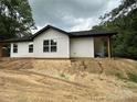 Side view of a home with white siding and a black roof on a cloudy day at 807 S Bostian St, China Grove, NC 28023