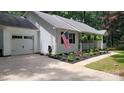 A well-maintained white home featuring a garage, American flag, and manicured garden at 109 Pepper Cir, Mooresville, NC 28117