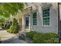 Charming brick townhouse featuring landscaped front yard, trimmed bushes, and a black front door at 1225 Assembly St, Belmont, NC 28012
