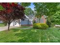 Landscaped front yard featuring beautiful plantings, mature trees, and a well-maintained lawn at 1310 Bellhook Nw Pl, Concord, NC 28027