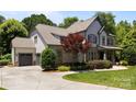 View of the house with a grey driveway, two-car garage, landscaped yard, and manicured lawn at 3009 Botetourt Ct, Weddington, NC 28104