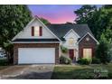 Two-story home with brick and siding exterior, two-car garage, and manicured lawn at dusk at 3428 Cranberry Nook Ct, Charlotte, NC 28269