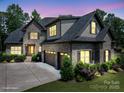 Charming gray brick home featuring a three-car garage, manicured lawn, and lush landscaping at 4143 Willow Haven Dr, Denver, NC 28037