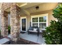 Inviting front porch with stone pillars, a black door, and a cozy seating area, perfect for relaxing outdoors at 4683 Dunberry Sw Pl, Concord, NC 28027