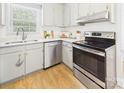 Cozy kitchen featuring stainless steel appliances, bright white cabinets, and a charming window above the sink at 4905 Chestnut Lake Dr, Charlotte, NC 28227
