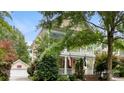 Two-story home with a welcoming front porch and balcony, surrounded by mature trees and lush landscaping at 6129 Caseys Side Way, Fort Mill, SC 29708