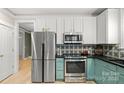 Kitchen featuring stainless steel appliances, accent-colored cabinets, and hardwood flooring throughout at 6129 Caseys Side Way, Fort Mill, SC 29708