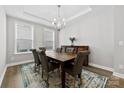 Bright dining room with a wooden table, two windows, chandelier, and a decorative cabinet at 6261 Six String Ct, Fort Mill, SC 29708