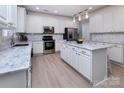 Bright kitchen featuring white cabinets, a marble island, stainless steel appliances, and modern lighting fixtures at 6914 Evanton Loch Rd, Charlotte, NC 28278