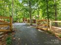 Long paved driveway leads to a garage, framed by an attractive wooden fence and green trees at 10710 Bristlecone Ct, Mint Hill, NC 28227