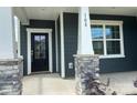 Inviting covered front porch with stone-accented columns and a stylish black front door entrance at 108 Red Juniper Way, Statesville, NC 28625