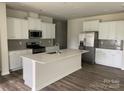 Modern kitchen with white cabinetry, stainless steel appliances, and a large center island with quartz countertop at 108 Red Juniper Way, Statesville, NC 28625