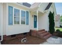 Inviting front porch with brick steps and blue door, complemented by fresh landscaping and a sunny view at 1083 Elljoy Ln, Salisbury, NC 28146