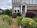 Close-up of a brick home with a welcoming front door and colorful flower beds at 1124 Greenbridge Dr, Matthews, NC 28105