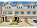 Exterior view of townhomes showcases a blend of brick and siding, complemented by attached garages and landscaping at 117 Langhorne Dr, Mount Holly, NC 28120