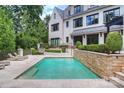 Backyard pool with stone retaining wall and steps to a patio with outdoor furniture at 11710 Ney Manor Way, Charlotte, NC 28277