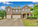 Charming brick home featuring a three-car garage, manicured lawn, and inviting front porch at 1355 Cilantro Ct, Fort Mill, SC 29708