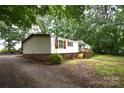 A manufactured home with a brick foundation, features a well-maintained exterior and a large, natural yard at 1789 Paris Dr, Conover, NC 28613