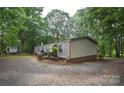 Exterior view of a charming single-level home with a gravel driveway and surrounded by tall, mature trees at 1789 Paris Dr, Conover, NC 28613