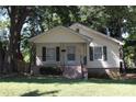 Inviting yellow home with covered porch, dark shutters, and neat landscaping at 606 E 4Th Ave, Gastonia, NC 28054