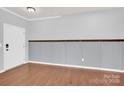 Empty room with gray walls, white door, and wood floors at 7101 Agnew Dr, Charlotte, NC 28273