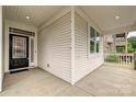 Inviting front porch featuring white siding, stone accents, and a stylish black front door at 2760 Berkhamstead Cir, Concord, NC 28027