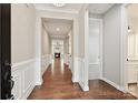 Elegant hallway with hardwood floors, wainscoting, and views of the living area with a fireplace at 2760 Berkhamstead Cir, Concord, NC 28027