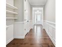 Bright hallway featuring hardwood floors, wainscoting, floating shelves and a view of the front door at 2760 Berkhamstead Cir, Concord, NC 28027