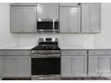 Close up of kitchen with stainless steel range, microwave and gray cabinets and subway tile backsplash at 300 Kennerly Center Dr, Mooresville, NC 28115