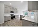 Modern kitchen featuring stainless steel appliances, gray cabinets, quartz countertops, and wood-style floors at 300 Kennerly Center Dr, Mooresville, NC 28115