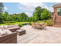 Outdoor patio with wicker furniture and a table, overlooking the manicured lawn and pool at 3009 Ocaso Ct, Matthews, NC 28104