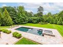 Inviting backyard pool and spa surrounded by lush greenery, manicured grass, and lounge chairs at 3009 Ocaso Ct, Matthews, NC 28104