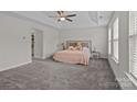 Spacious primary bedroom with plush carpeting, a tray ceiling, and a walk-in closet at 308 Planters Way, Mount Holly, NC 28120