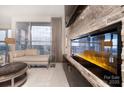 Cozy living room with a stone accent wall, a sleek fireplace, and a large window showcasing city views at 333 W Trade St # 1304, Charlotte, NC 28202