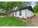 Charming white brick home featuring black accents, manicured landscaping, and a bright red front door at 3900 Colebrook Rd, Charlotte, NC 28215