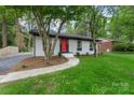 Beautifully renovated home with white painted brick, a red front door, and lush green lawn at 3900 Colebrook Rd, Charlotte, NC 28215