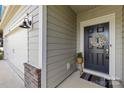 Close-up of the front door with wreath, neutral siding, and a carriage light for warm curb appeal at 3938 Isenhour Rd, Kannapolis, NC 28081