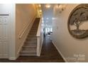 Inviting foyer featuring wood floors, staircase, neutral walls, and decorative wall art at 4637 Willow Glen Rd, Harrisburg, NC 28075