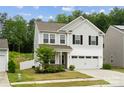 Two-story home featuring neutral siding, two-car garage, established landscaping, and a well-maintained lawn at 5113 Saddleback Dr, Mount Holly, NC 28120