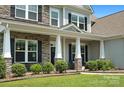 Inviting front porch with stone supports, black shutters, and manicured landscaping at 6535 Bridgemoor Dr, Indian Trail, NC 28079