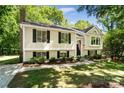 Charming two-story home with light yellow siding, black shutters, and an American flag at 7018 Rollingridge Dr, Charlotte, NC 28211