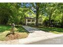Traditional two-story home with light siding nestled among mature trees and a paved driveway at 7018 Rollingridge Dr, Charlotte, NC 28211