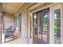 Charming front porch entrance with rocking chairs, brick and stone, and view to the yard at 8070 Clems Branch Rd, Indian Land, SC 29707