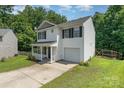 Side view of a two-story home featuring vinyl siding and an attached garage, surrounded by lush greenery at 8524 Emerald Fern Way, Charlotte, NC 28214