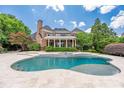 A luxurious backyard features a large pool with a spa and travertine tile, perfect for outdoor relaxation at 8721 Lake Challis Ln, Charlotte, NC 28226