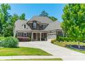 Charming home featuring mature landscaping, a gray and stone facade, and a spacious driveway at 1812 Sutter Creek Dr, Waxhaw, NC 28173