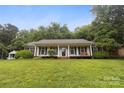 Inviting home with a covered front porch, surrounded by lush greenery at 1821 Bonnie Ln, Charlotte, NC 28213