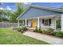 Inviting front porch with rocking chairs and a cheerful yellow door, surrounded by lush landscaping and a brick-lined flowerbed at 2302 Douglas Rd, Lancaster, SC 29720